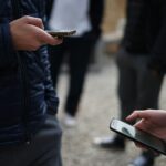 person in black jacket holding white smartphone